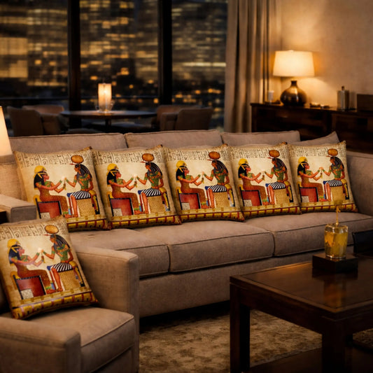 Decorative pillows with ISIS and Hathor  designs on a gray sofa in a room with a cityscape view.